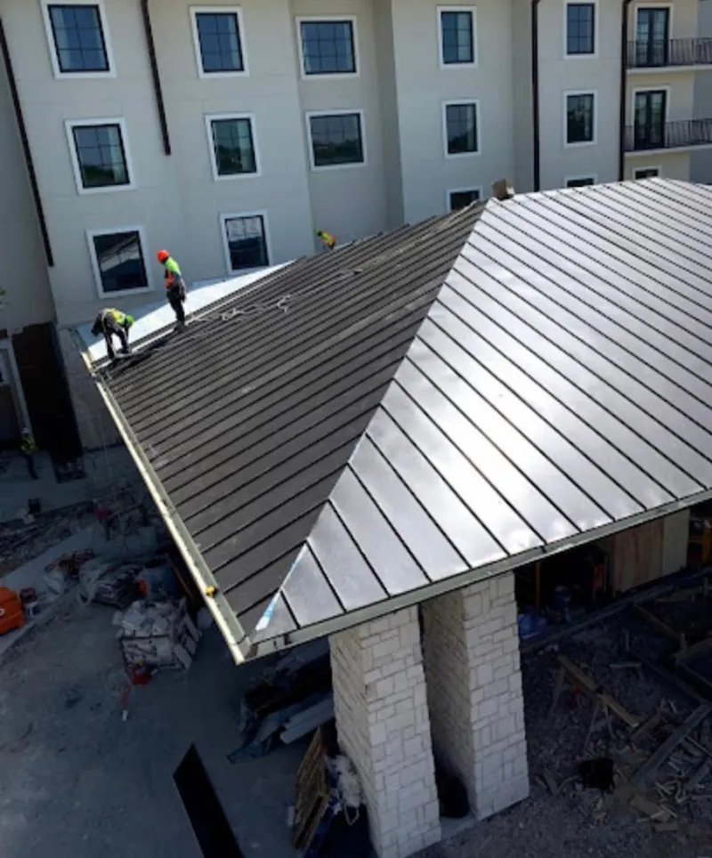 Crew installing standing seam metal roof panels on a commercial project in Murray